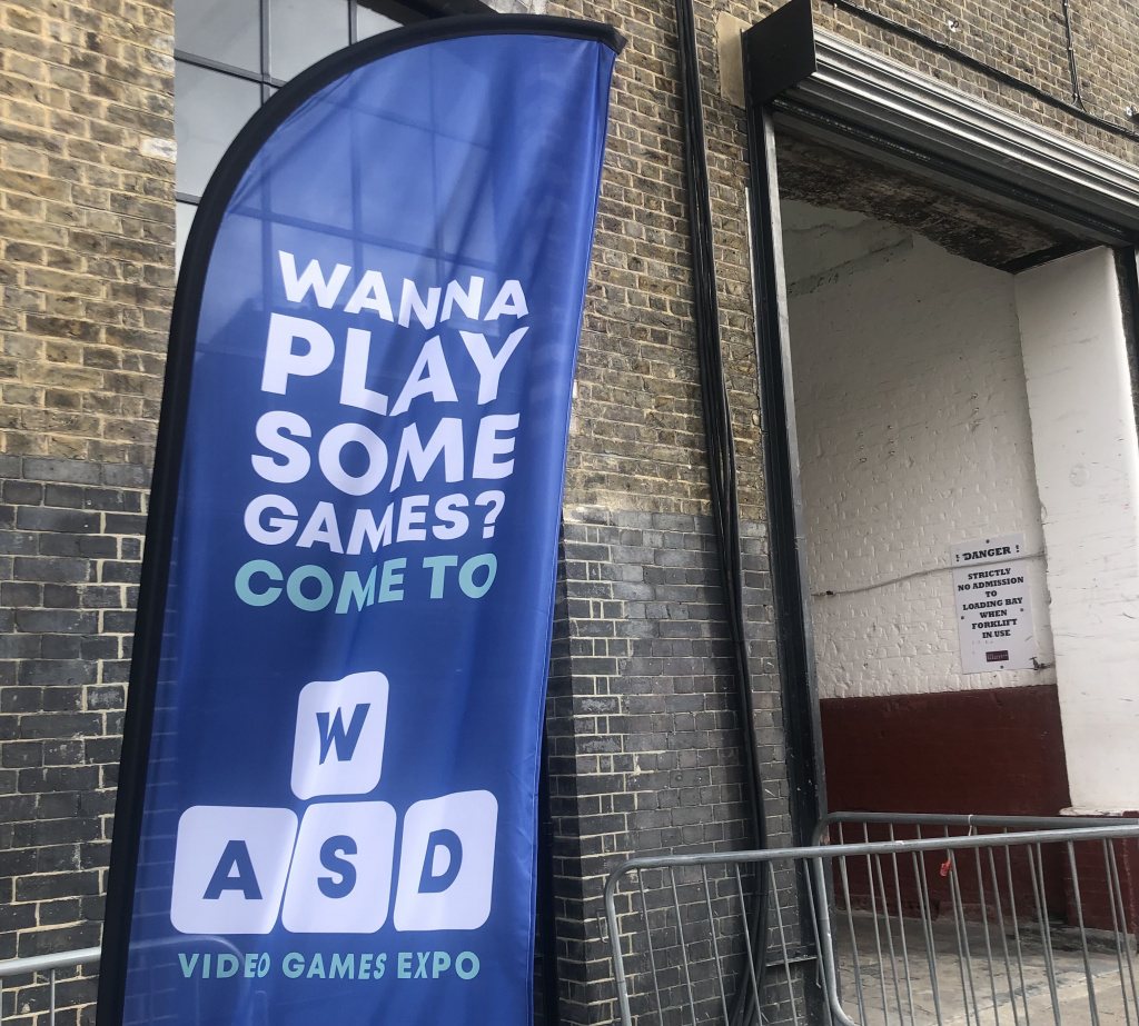 Publisher Collective at WASD Flag banner that reads 'Wanna play some games? Come to W.A.S.D. Video Games Expo.'